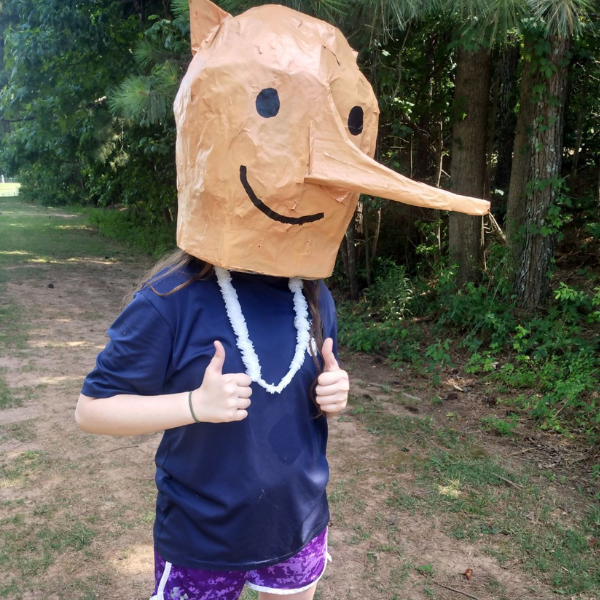 Young woman with paper mache mask in the woods