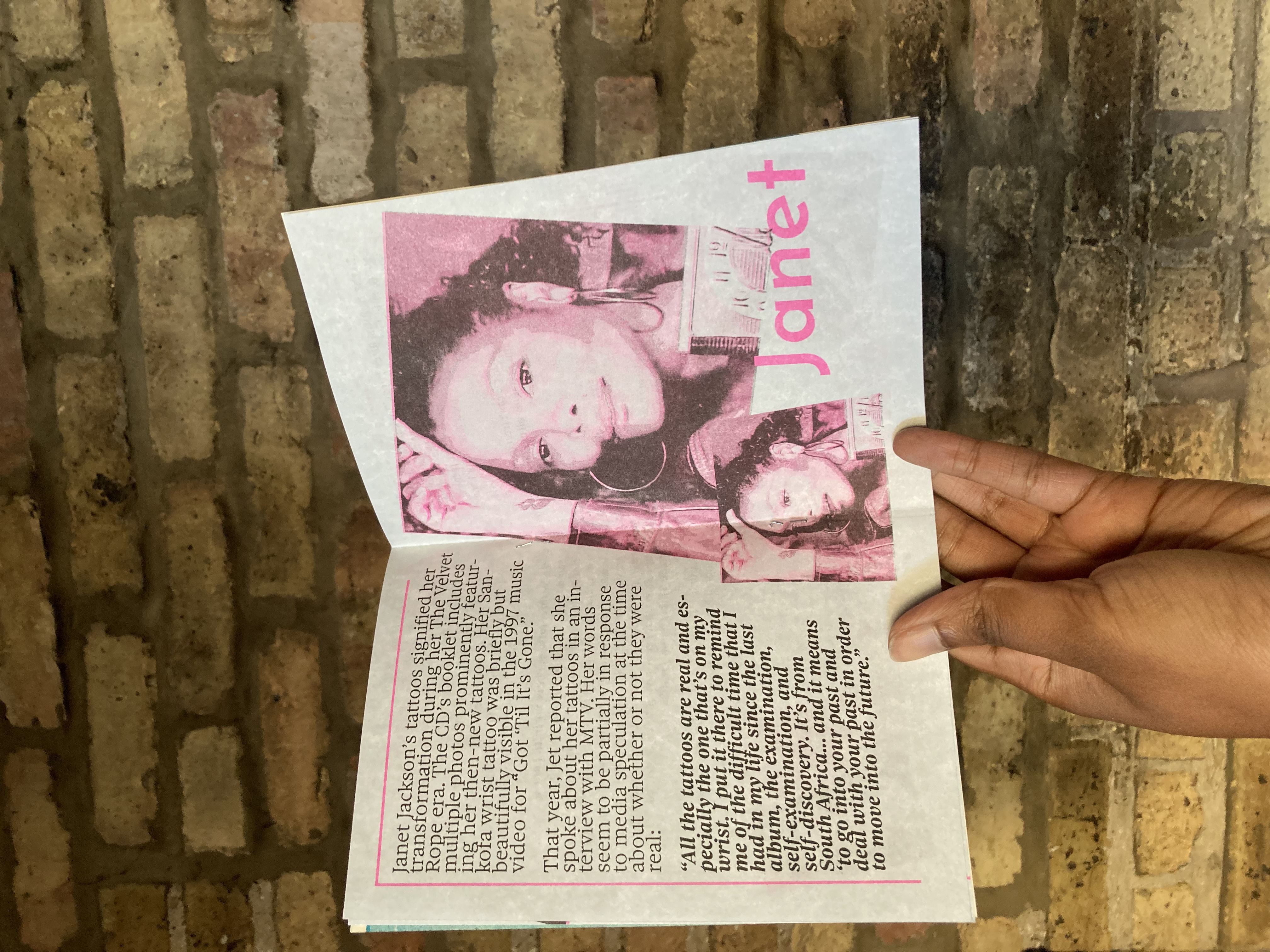 The centerfold of Tatted featuring two images of Janet Jackson showing the tattoo on her wrist. The pages frature a quote from Janet Jackson talking about her tattoos.