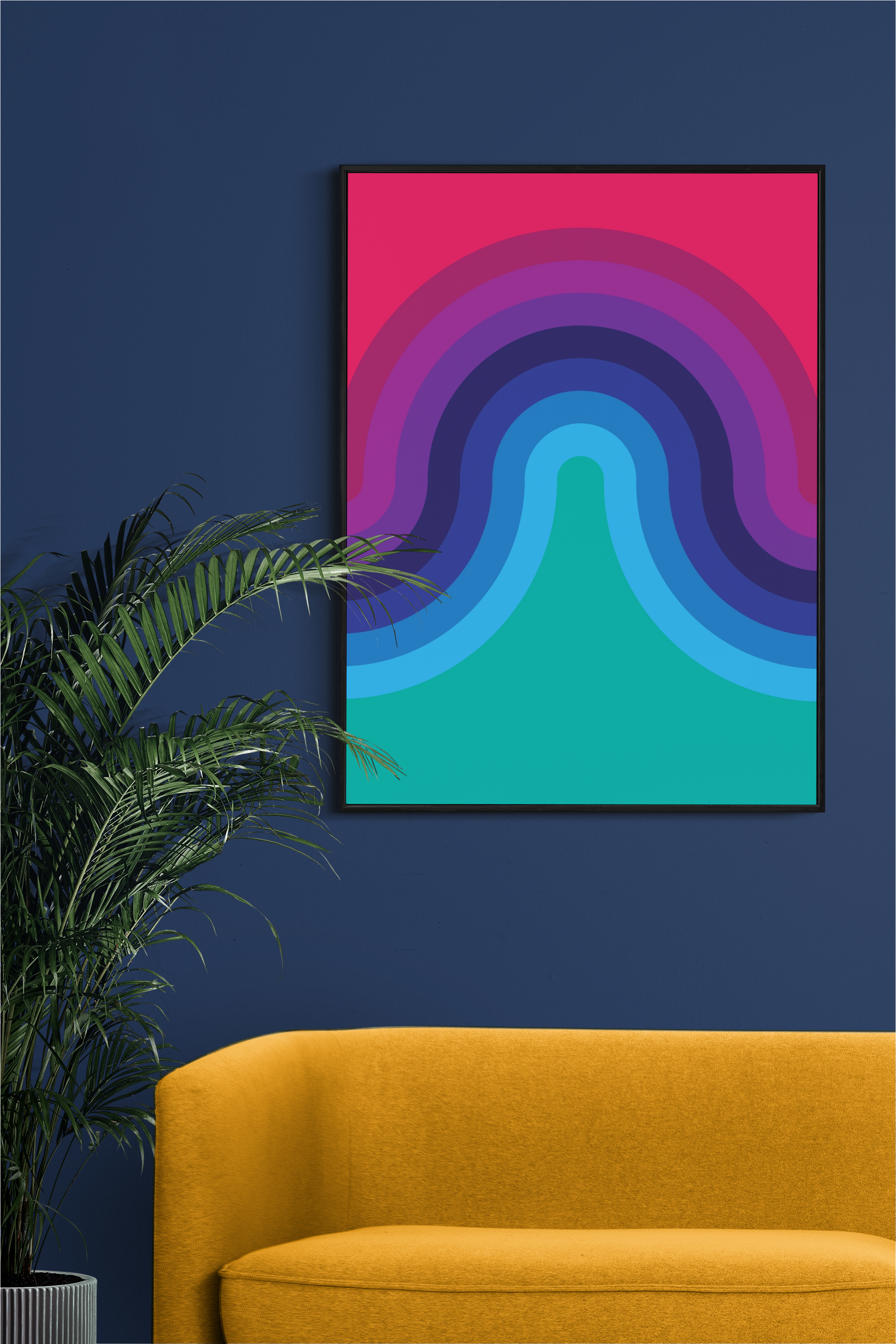 The image shows a framed artwork with a colorful, abstract design featuring layered wave-like shapes in various shades of blue, purple, and teal, transitioning to a pink background. The artwork is displayed on a dark blue wall, accompanied by a yellow sofa and a green potted plant, creating a bold and vibrant color contrast.