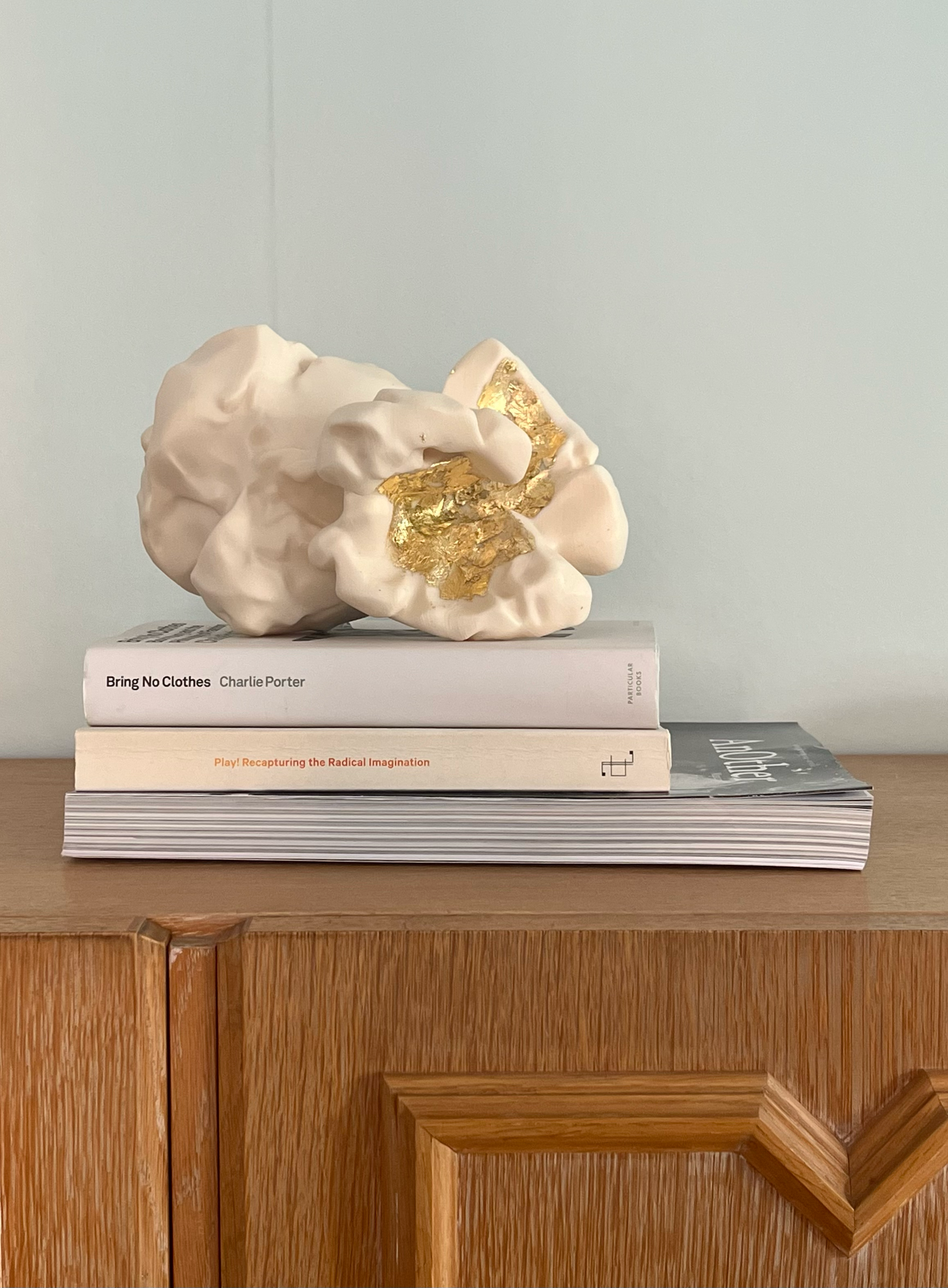 Gilded Popcorn on top of Books and a magazine on a shelf.