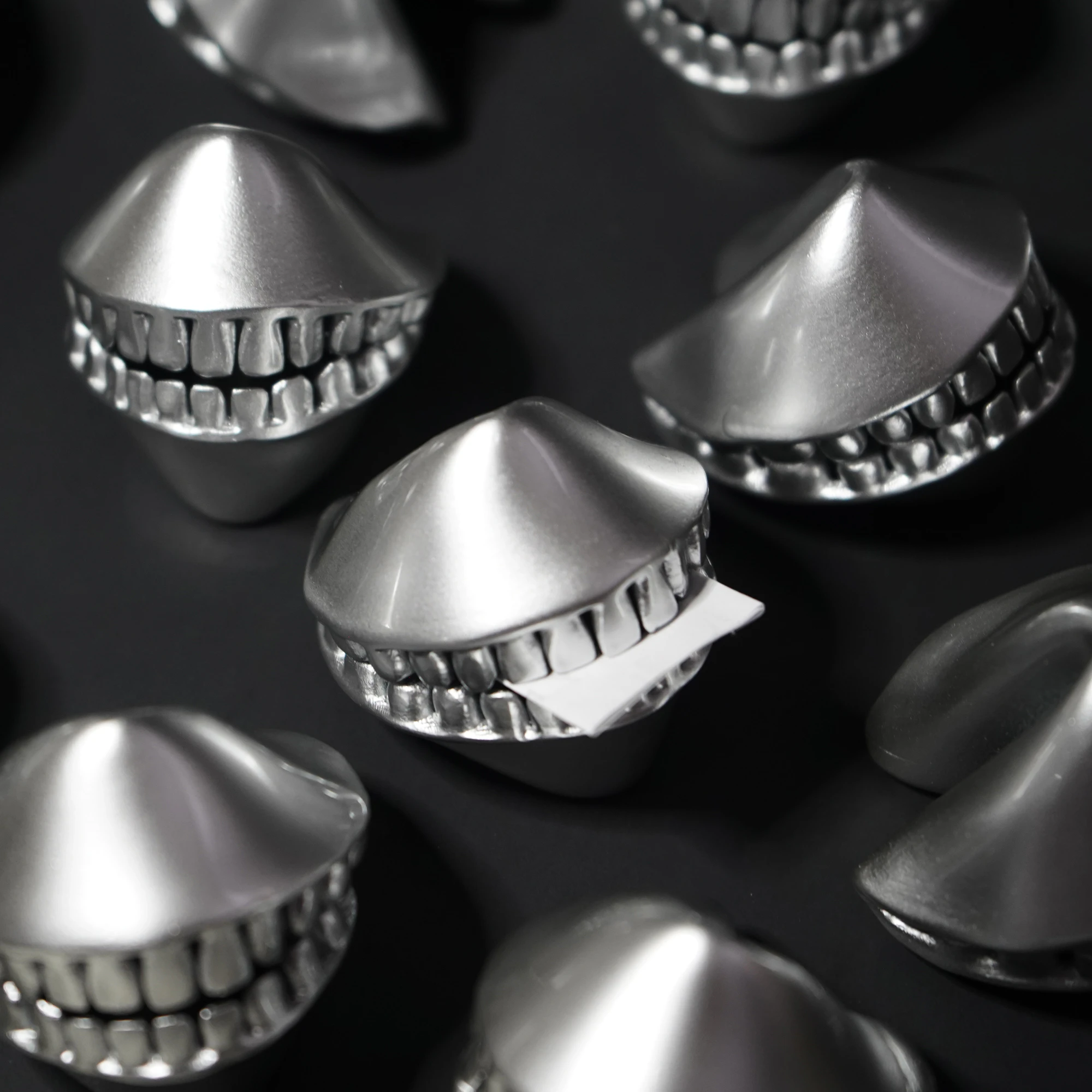 toothy fortune cookie with metallic silver finish grinding a piece of tweet