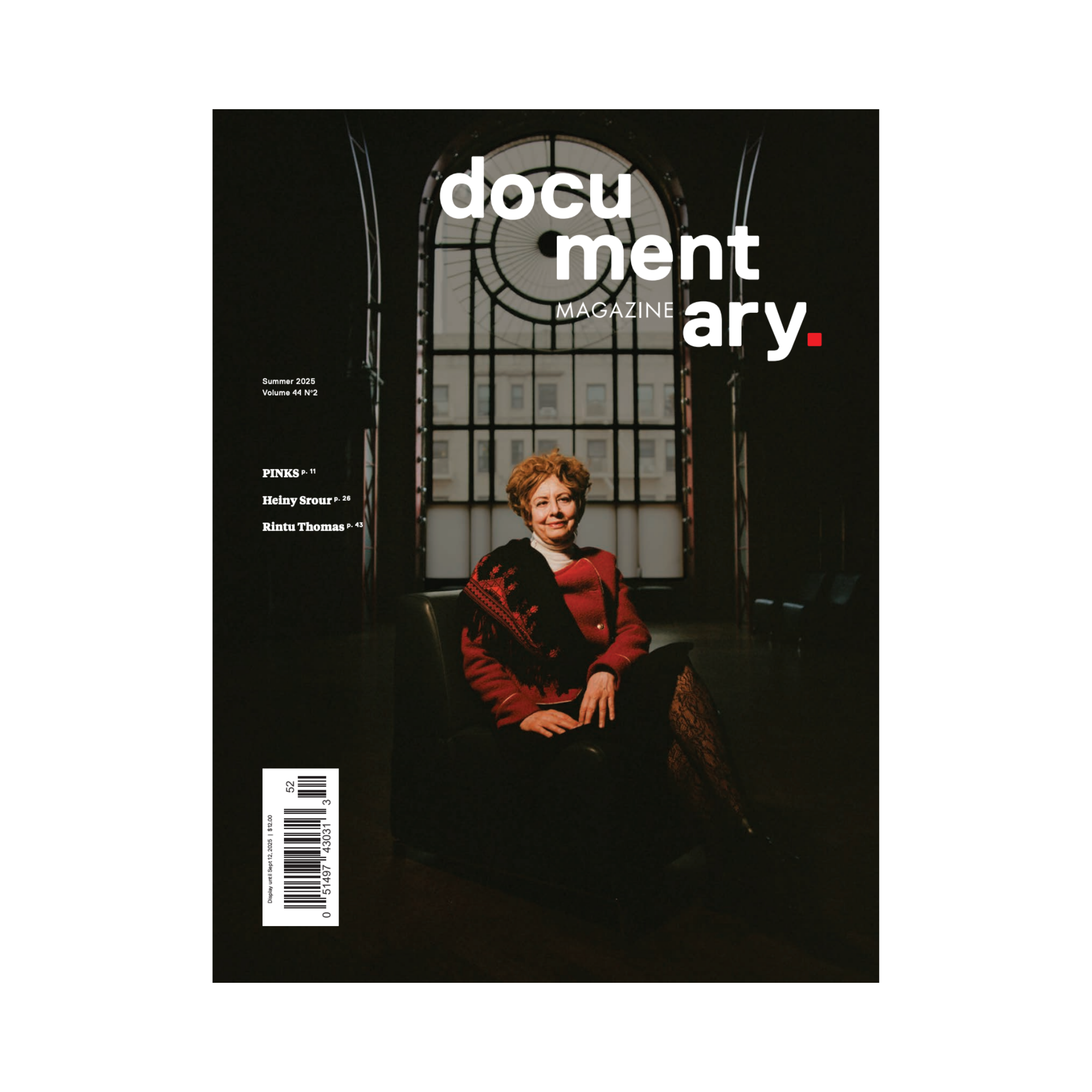 Magazine cover depicting a woman with curly auburn hair, dressed in a red coat with a black and red shawl, sitting regally in front of a giant glass window (Brooklyn Academy of Music).