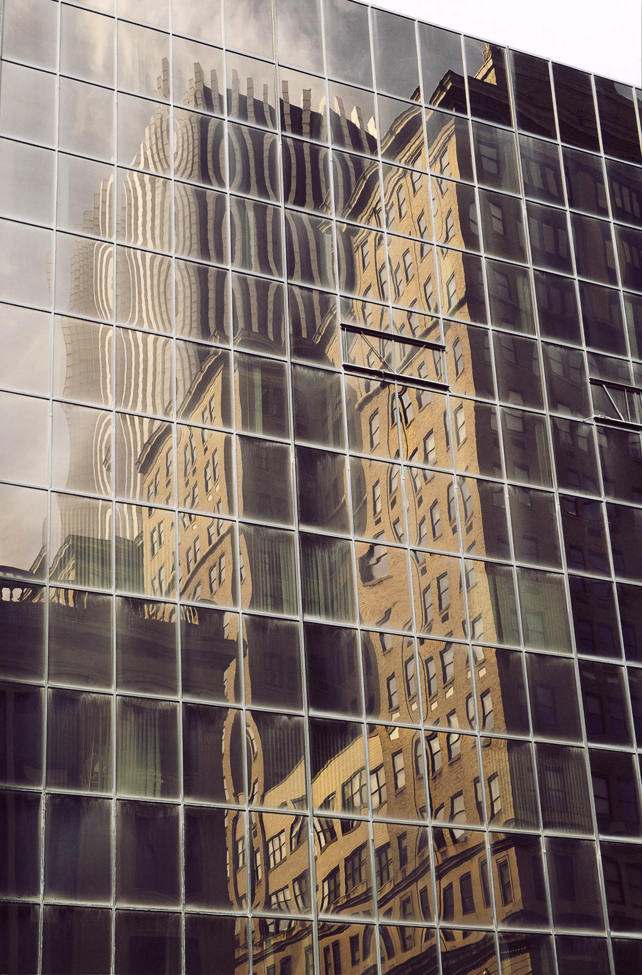 A glass facade mirros buildings that appear to be warped.