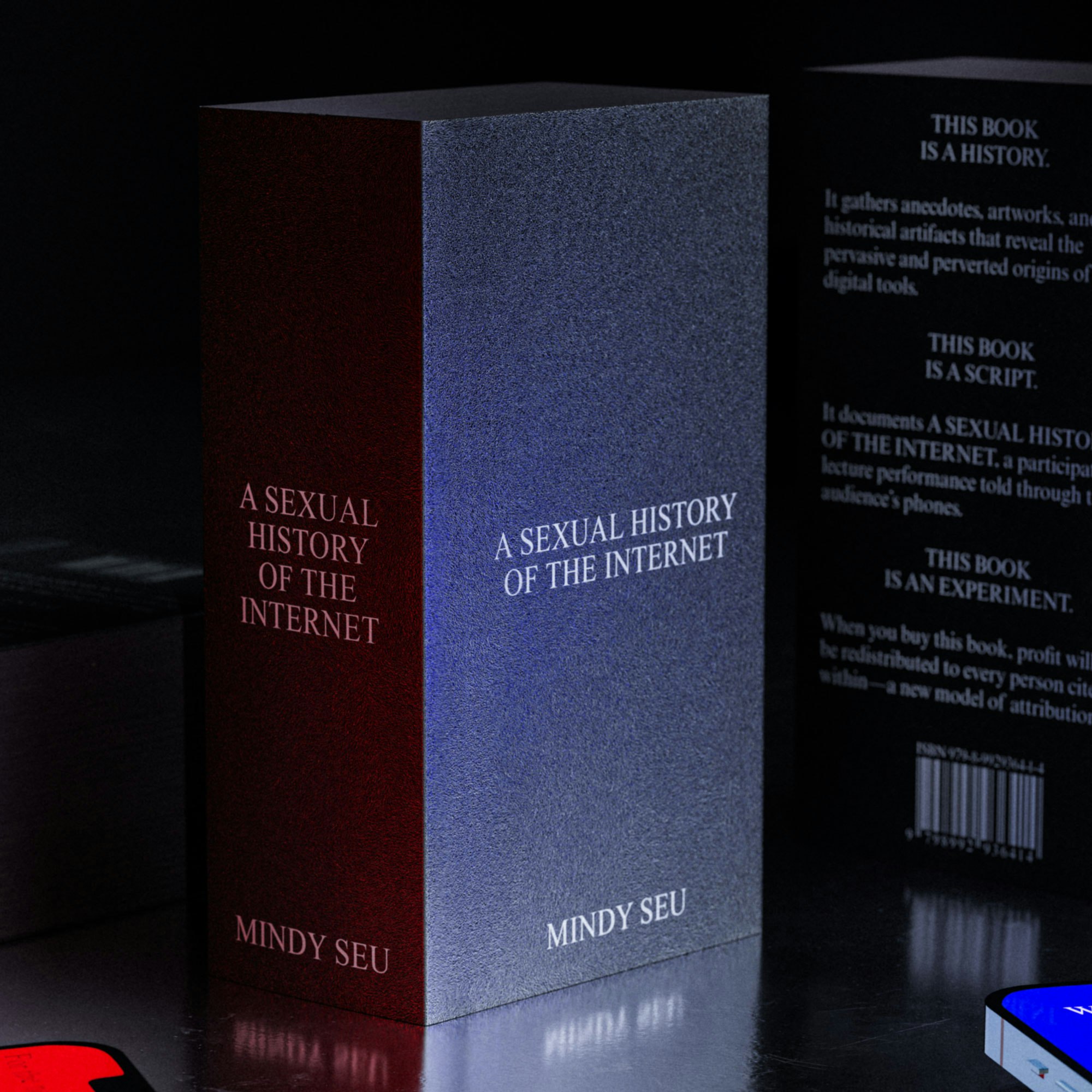 A black book called A SEXUAL HISTORY OF THE INTERNET standing on a metal table surrounded by two phones with red and blue screens